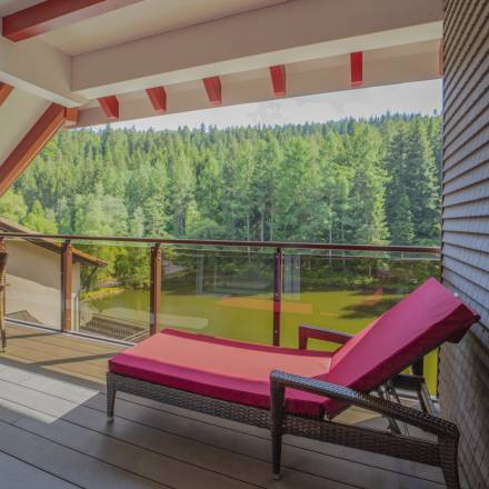 Balkon mit Liegestuhl und Blick auf den See
