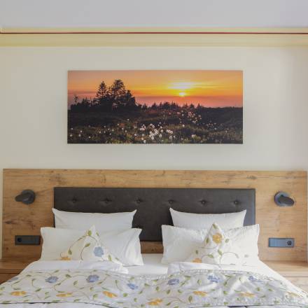 Hotelbett mit Blumenbettwäsche und Panorama Bild darüber