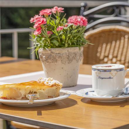 Leckerer Apfel-Käse-Kuchen auf Teller mit einem Cappuccino 