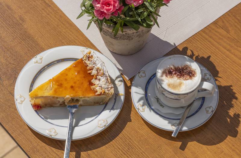 Kuchenstück auf Teller und Cappuccino auf Tisch
